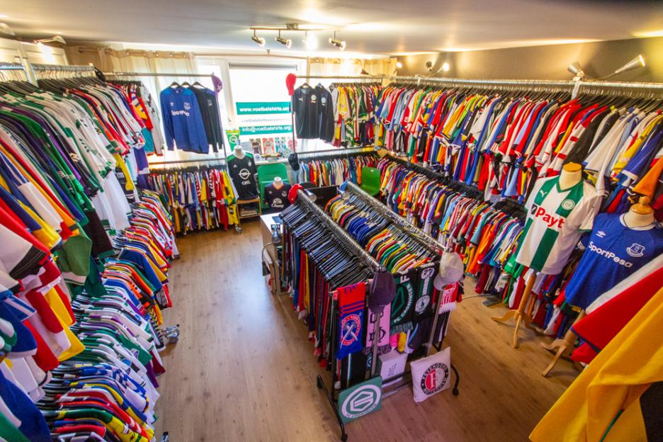 An indoor shop with racks of soccer jerseys and scarves.