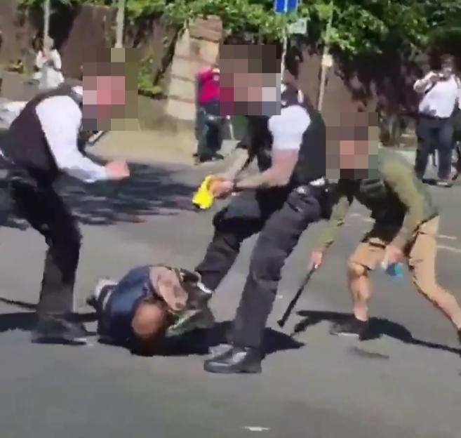 Police officers detaining a suspect on the ground in Golders Green.
