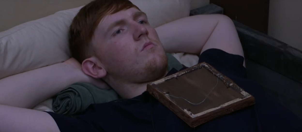 Angry Ginge lying down with a framed photo on his chest.