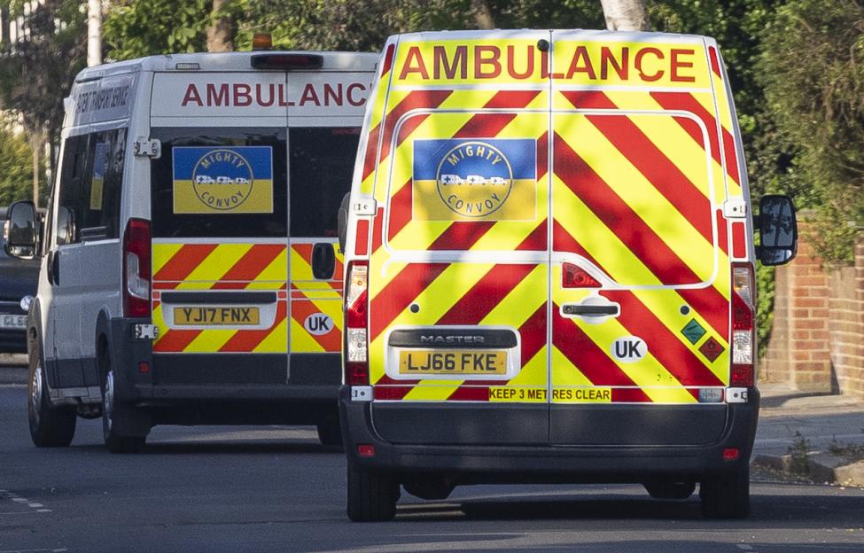 Two "Mighty Convoy" ambulances, with Ukrainian flag stickers, driving away.