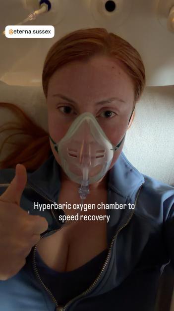 A person wearing an oxygen mask gives a thumbs-up in a hyperbaric oxygen chamber.