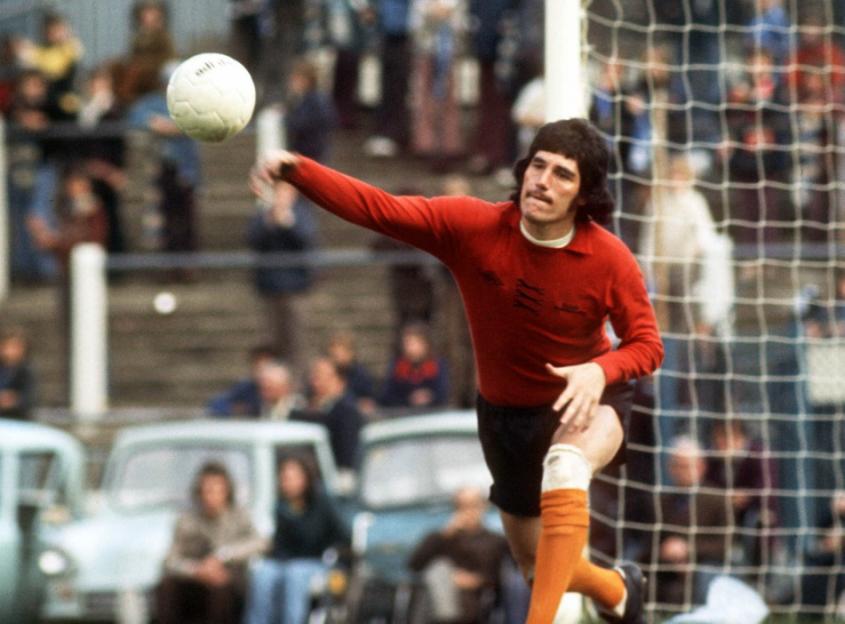 Footballer Pat Jennings, in a red jersey, throwing a soccer ball during a game.