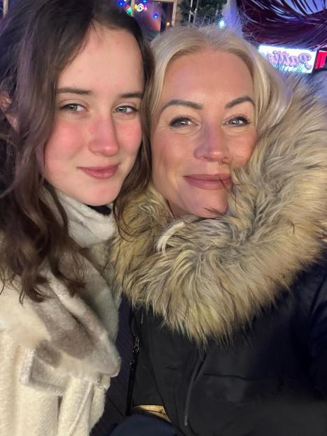 A mother and daughter smiling in winter clothes.