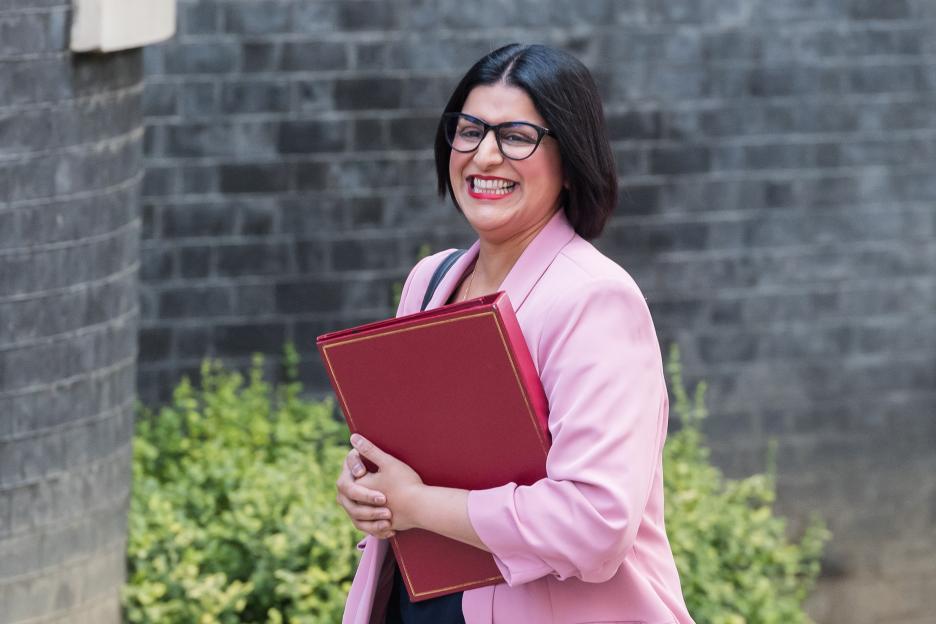 Shabana Mahmood, Secretary of State for the Home Department, smiling while holding a red folder.
