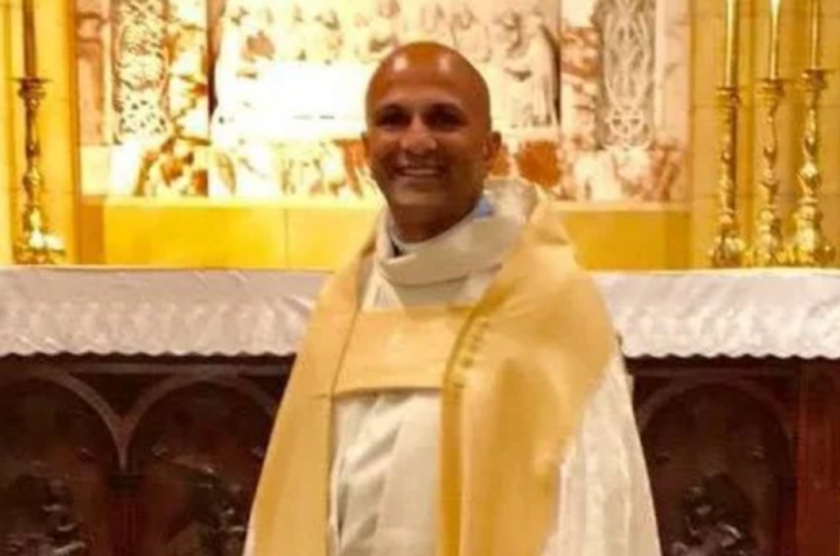 Kesh Govan smiling while wearing vestments in a church.
