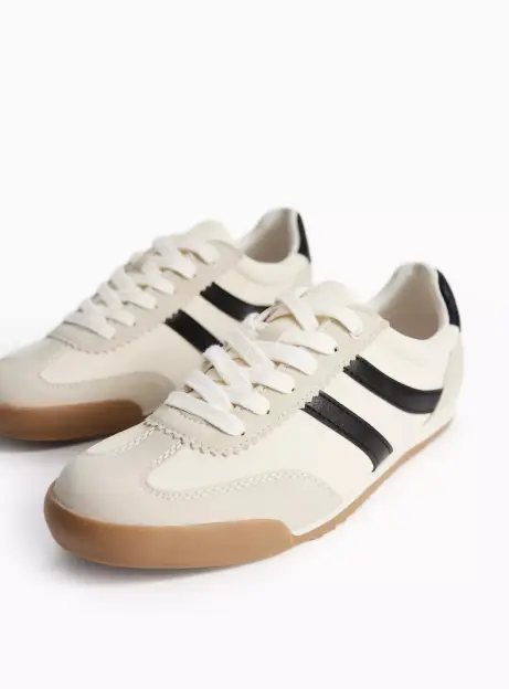 A pair of off-white trainers with black stripes and brown soles.