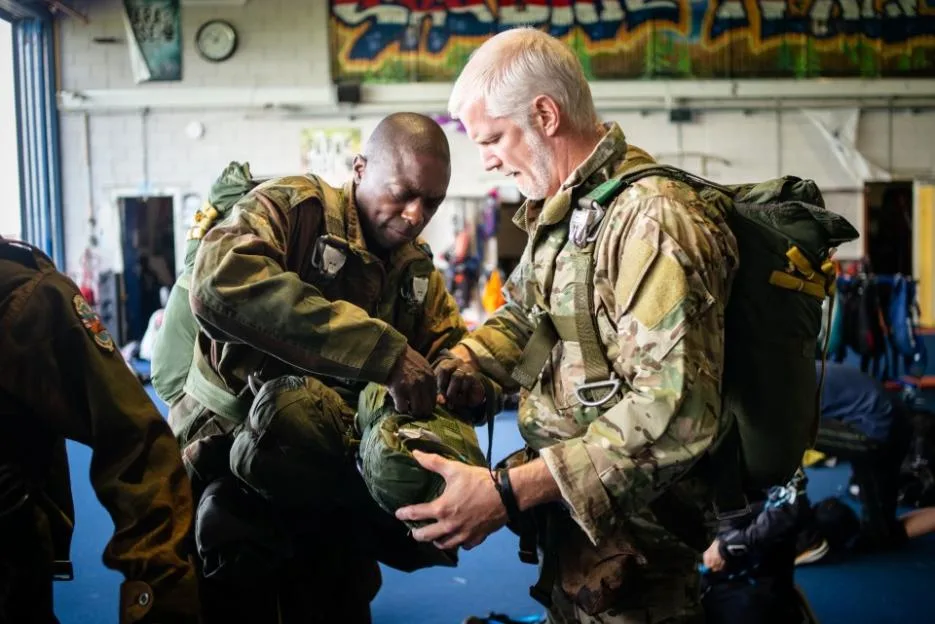MPs Al Carns and Bayo Alaba checking each other's parachutes.