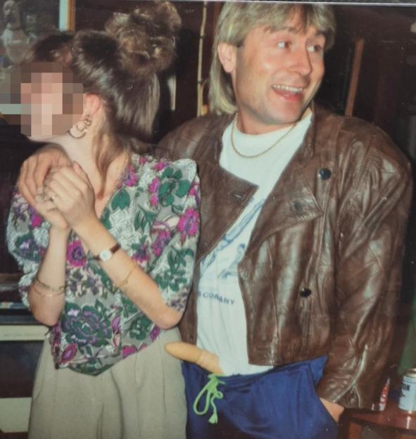 Jon Worboys in a brown leather jacket, with his arm around a woman, and a banana protruding from his blue shorts.