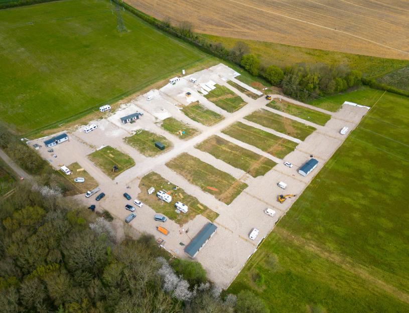Aerial view of a new travellers' camp with caravans, mobile homes, and construction machinery in Flamstead.