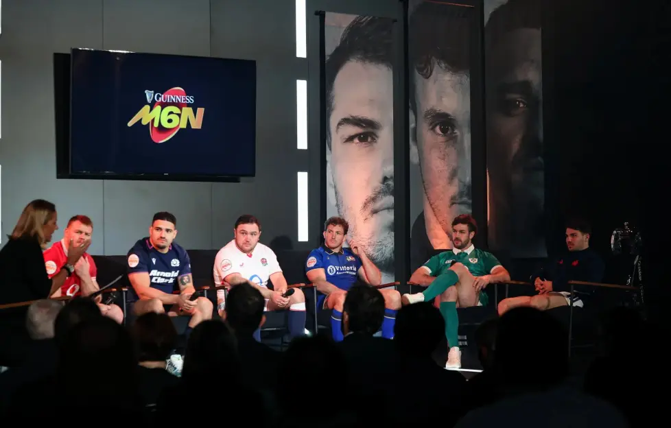 Six Nations rugby players on a panel discussion, with a large screen displaying the Guinness M6N logo.