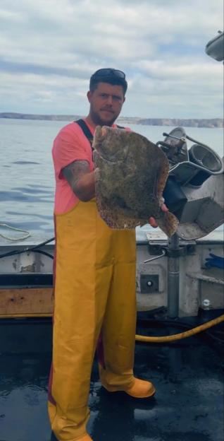 Daniel Gilbert, a fisherman, holds up a large flatfish.