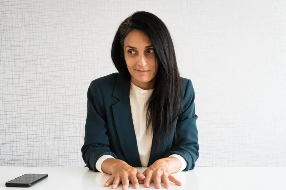 A young business woman with an uncertain expression at work.