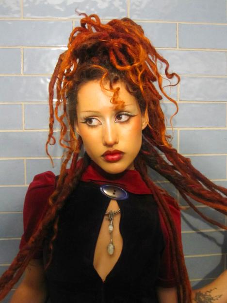 THE ABSOLUTELY AKA ABBY-LYNN KEEN with reddish-orange dreadlocks and a dramatic eyeliner look.