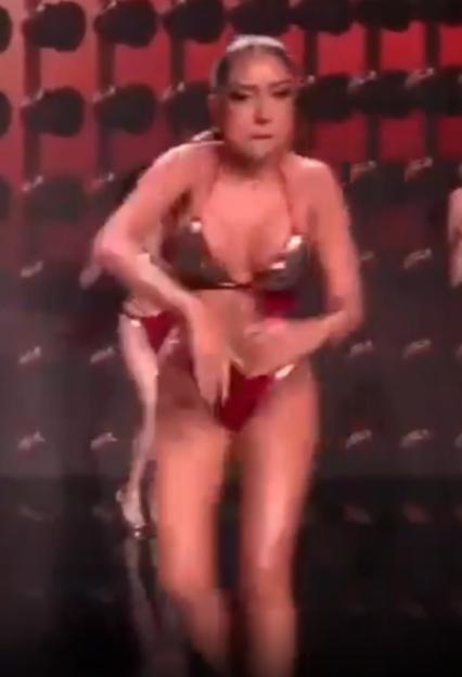 Woman in a shiny bikini dancing on a stage.