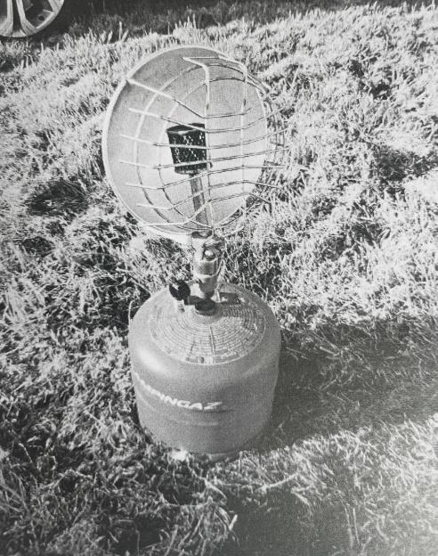 A black and white image of a portable gas heater on a patch of grass.