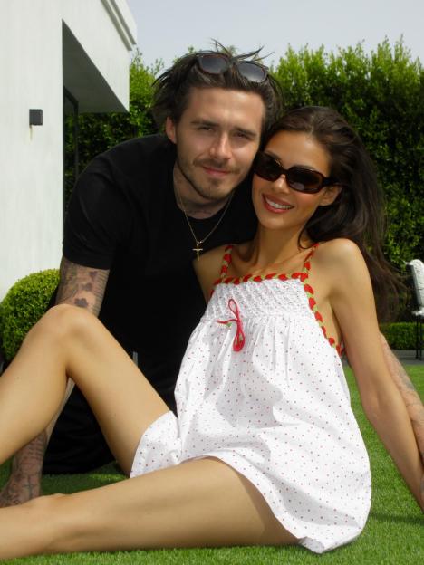 Nicola Peltz Beckham posing with Brooklyn Beckham on grass.