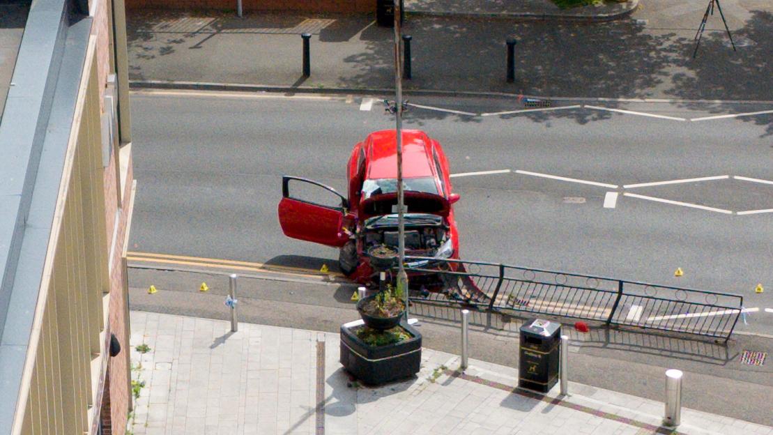 A police car is parked in front of a brick building with "b&m" sign.
