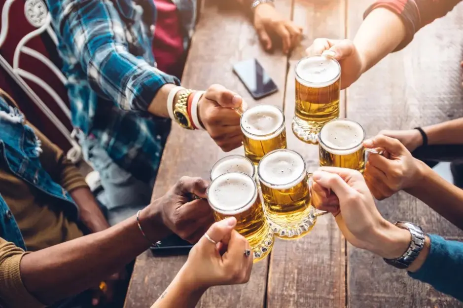 A group of young people toasting with mugs of beer.