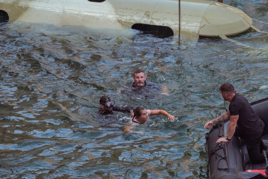 DS Rudy helping Dani Dyer into a boat, holding DS Chris, with Ryan Moloney in the water behind them.