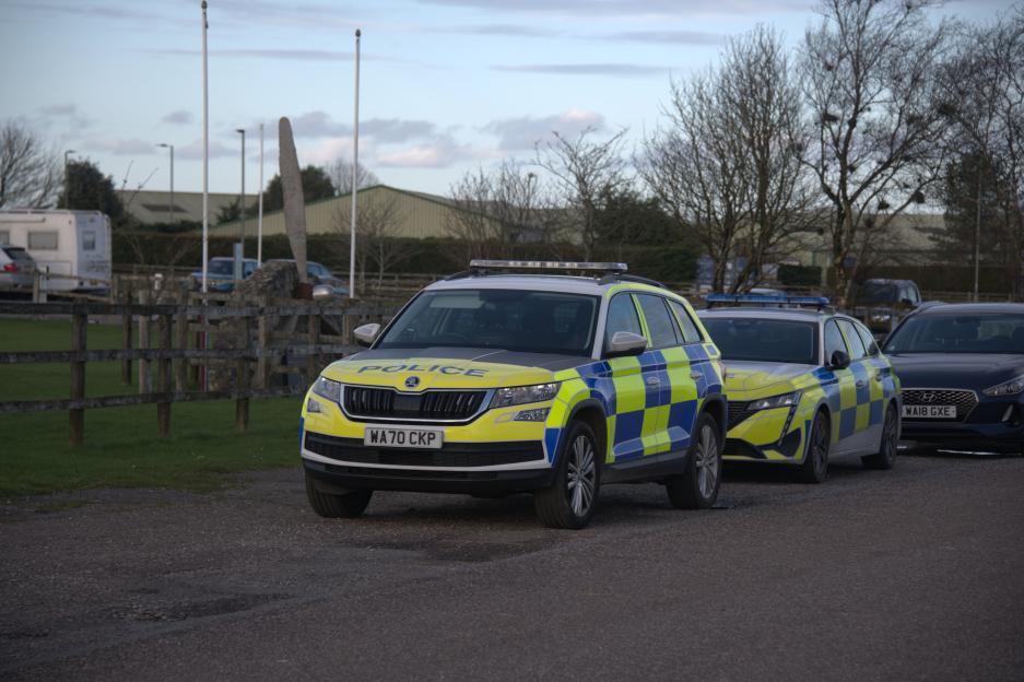 Police vehicles parked at Dunkeswell Aerodrome in East Devon.