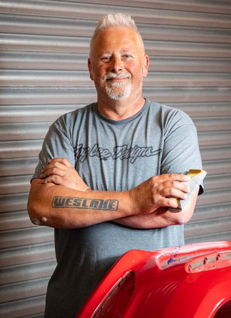 Martyn Smith, owner of MPS Body & Paint, in his garage with a red car part.