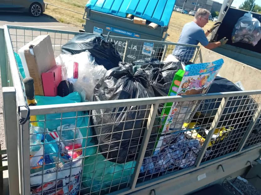 A man unloads rubbish into a dumpster.