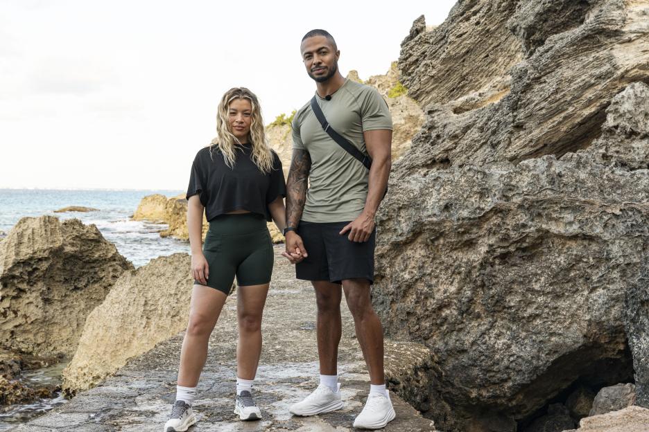 Molly Rainford and Tyler West standing on a rocky shore.