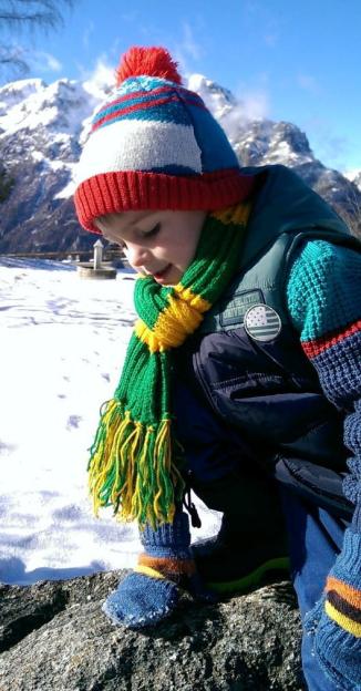 Finnbar Cork, a young boy in winter clothing, plays in the snow with mountains in the background.