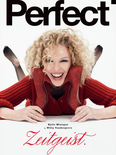 Kylie Minogue smiling, with red knitwear and red crystal-studded shoes, for Perfect Magazine.