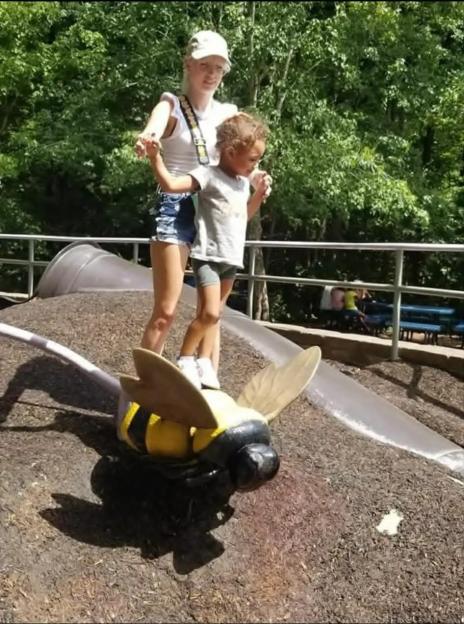 Katlyn Sale and daughter Milani posing by a bee toy at a playground.