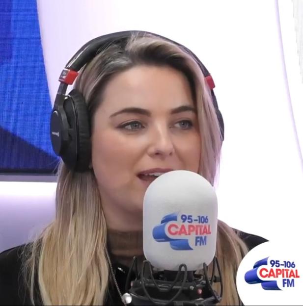 Sian Welby, Capital FM presenter, wearing headphones and speaking into a Capital FM branded microphone.