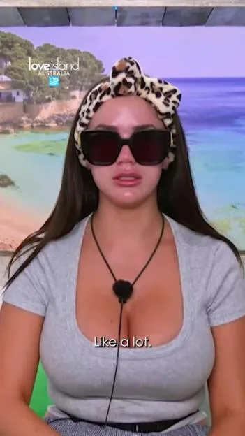 A woman wearing sunglasses and a leopard print headscarf with the "Love Island Australia" logo in the background.