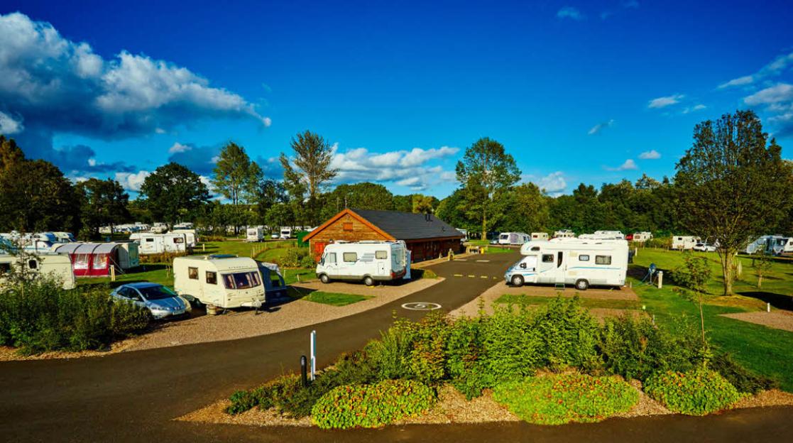 Strathclyde Country Park Club Campsite in Bothwell, Glasgow, Scotland, with numerous parked caravans and motorhomes on a sunny day.