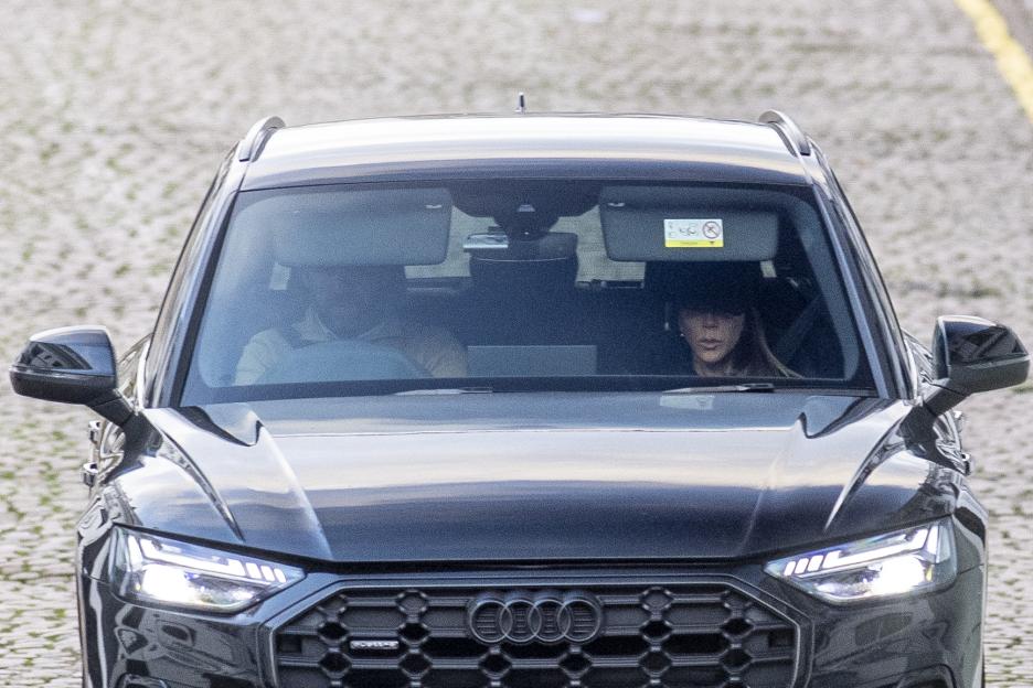 Victoria Beckham looking downcast while being driven in a car.