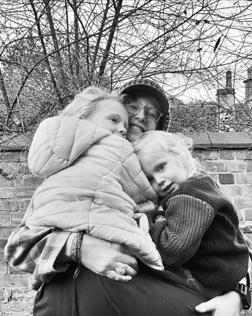 Black and white photo of a smiling mother holding her two children.