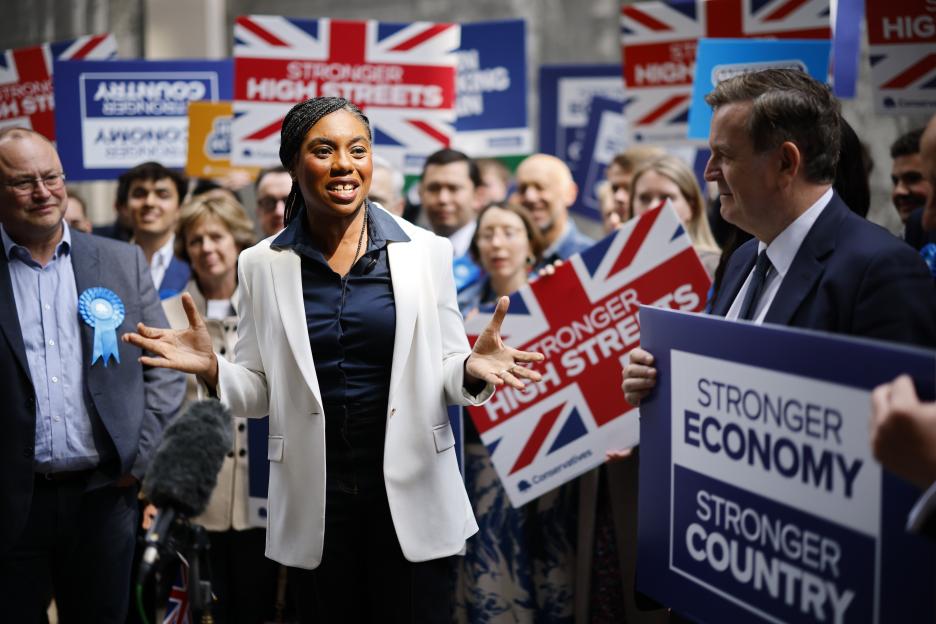 Kemi Badenoch, leader of the British Conservative Party, speaking to the media surrounded by supporters holding "Stronger High Streets" and "Stronger Economy, Stronger Country" signs.