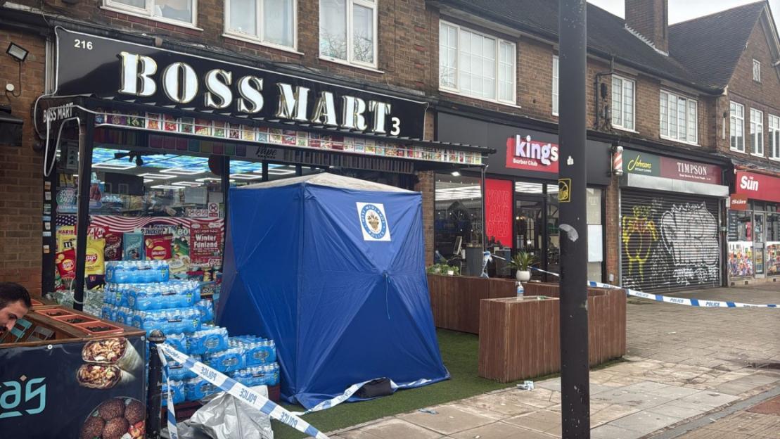 Police tent set up in front of a Boss Mart convenience store, with police tape around the area.