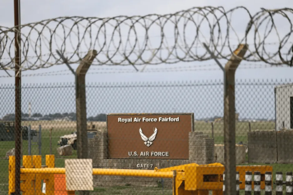 Sign for Royal Air Force Fairford and U.S. Air Force, Gate 7, behind a barbed wire fence.
