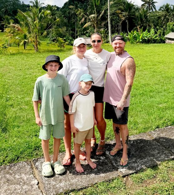 The Oxley family with their three children in Bali, surrounded by lush green landscapes and palm trees.