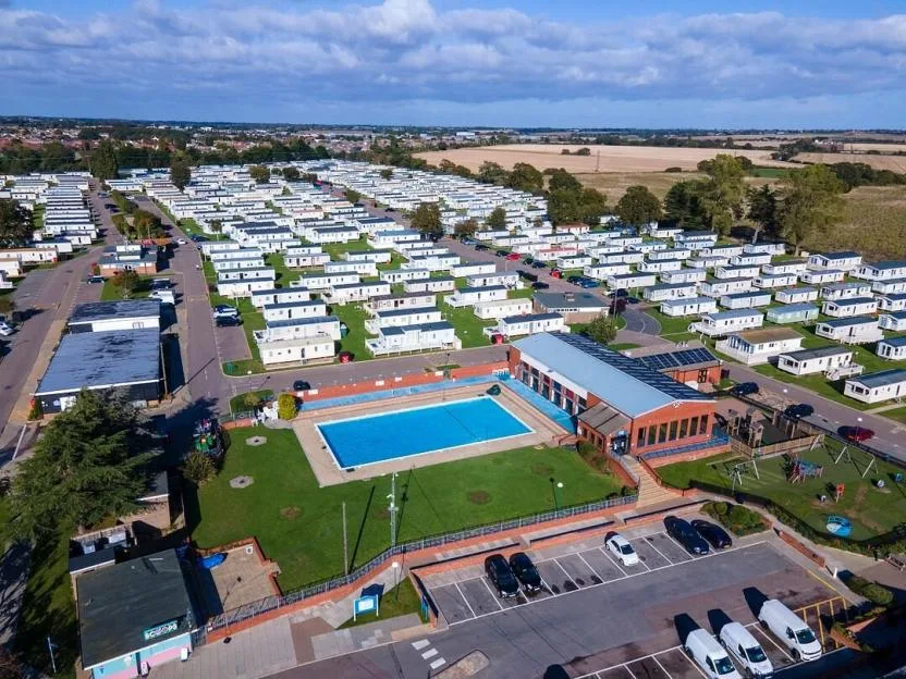 Aerial view of Valley Farm Holiday Park, showing a large outdoor swimming pool, a leisure complex, and rows of holiday caravans.