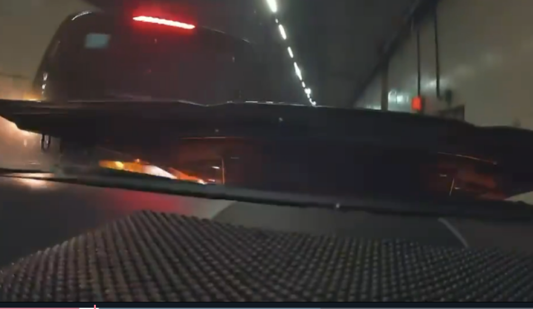 A black train with red lights traveling through a tunnel.