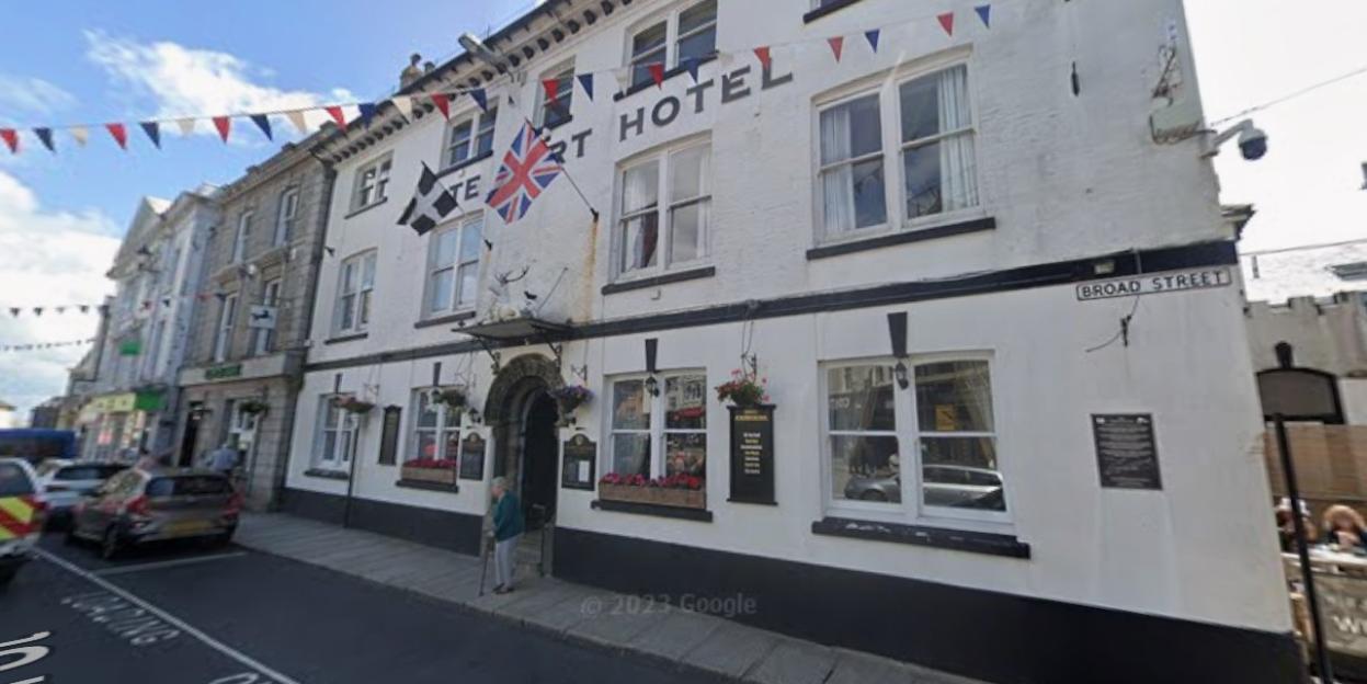 White Hart Hotel in Launceston, marked with a Union Jack flag and "Broad Street" sign.