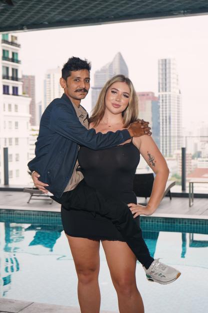 Amira Evans, a 6'7" woman in a black dress, holds a shorter man with a mustache on her hip.