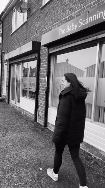 A person walking past "The Baby Scanning" building.