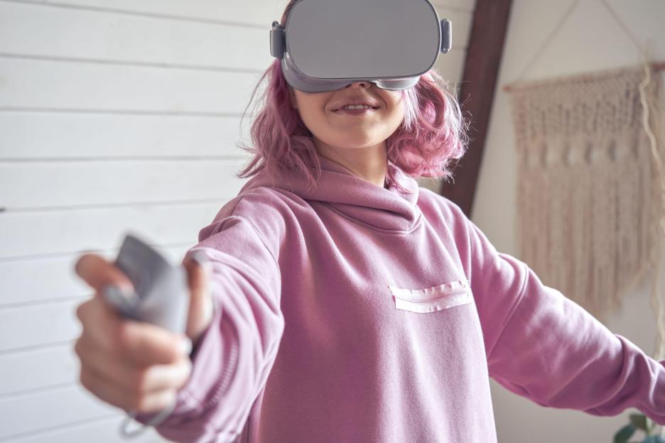 Teen girl wear vr goggles hold controller playing virtual reality game.