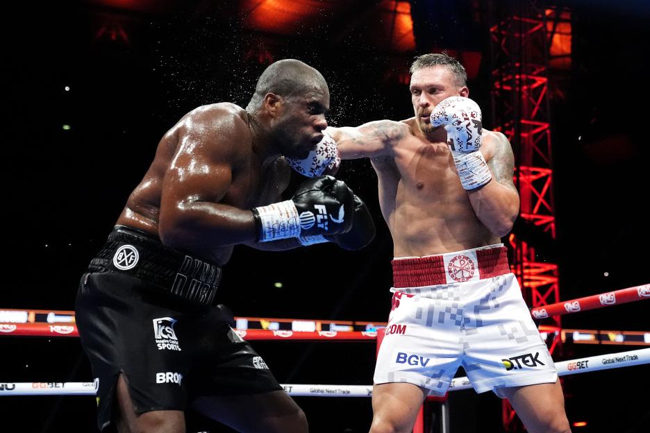 Oleksandr Usyk (right) punches Daniel Dubois (left) during a boxing match.