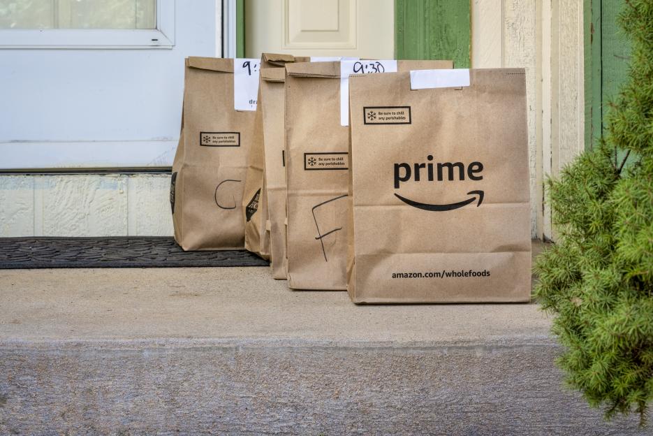 Grocery delivery bags from Whole Foods Market and Amazon Prime on a doorstep.