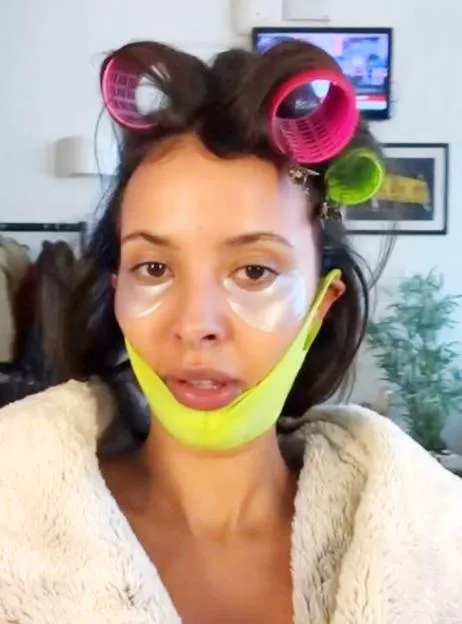 Maya Jama wears hair rollers, under-eye patches, and a lime green chin strap.