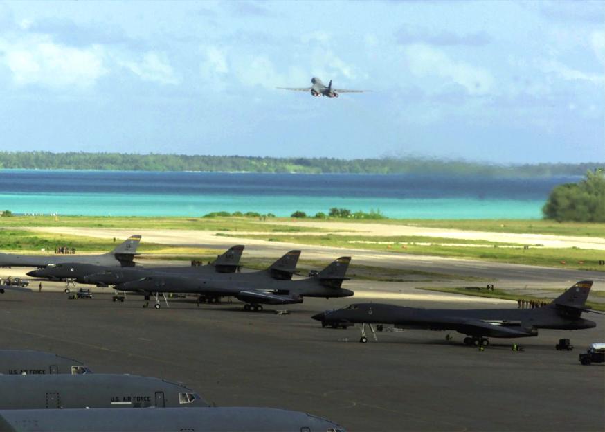 Military aircraft on the runway of Diego Garcia, with a bomber taking off over the turquoise Indian Ocean.