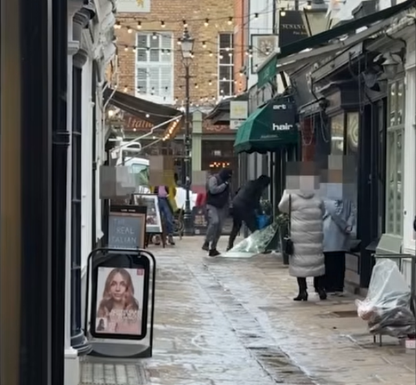 Two men smashing the window of a jewelry store with a sledgehammer to rob it.